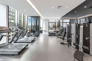 Ein modernes Fitnessstudio mit Laufbändern, Kraftgeräten und einer Bank.