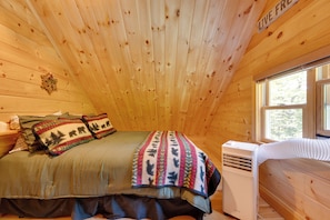 Une chambre confortable dans un chalet, avec un lit, une fenêtre et un radiateur fixé au mur.