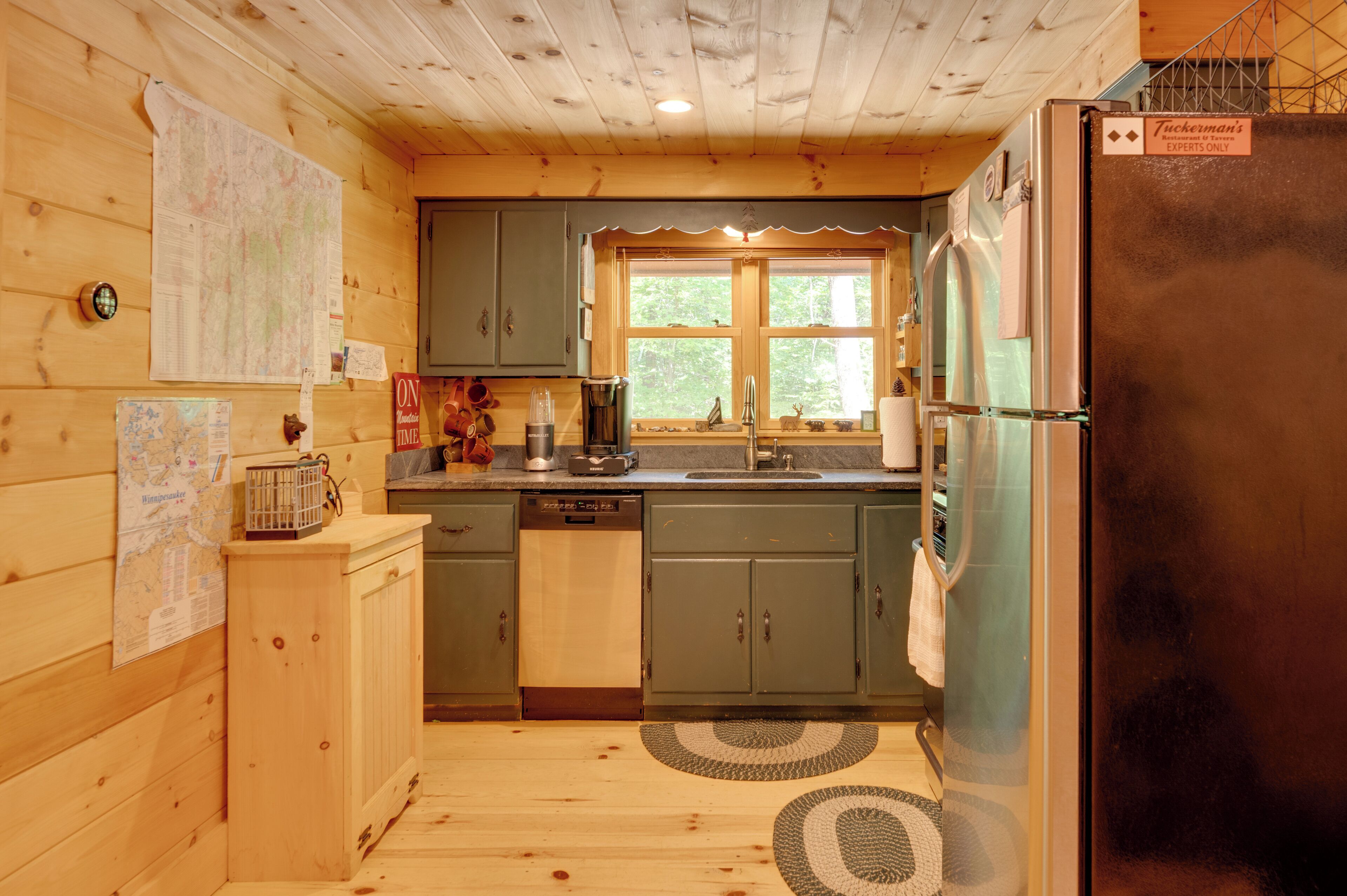 Una cocina compacta con muebles de madera, lavavajillas integrado y refrigerador.