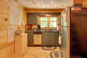 Eine kleine Küche mit Holzschränken, einem integrierten Geschirrspüler und einem Kühlschrank.