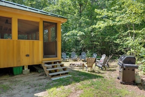 Une cabane dotée d’une véranda, d’un espace salon extérieur et d’un barbecue.