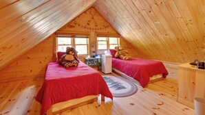 A cozy attic bedroom with two beds, a heater, and a window. - North Conway: Updated 3BR Cabin Sleeps 9, Fire Pit (North Conway)