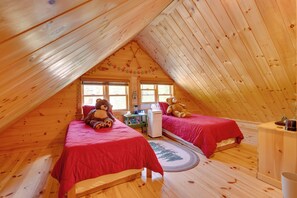 Ein gemütliches Schlafzimmer im Dachgeschoss mit zwei Betten, einem Heizkörper und einem Fenster.