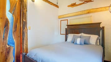 A bedroom with a wooden headboard, a bed with grey bedding, and a wooden wall accent.