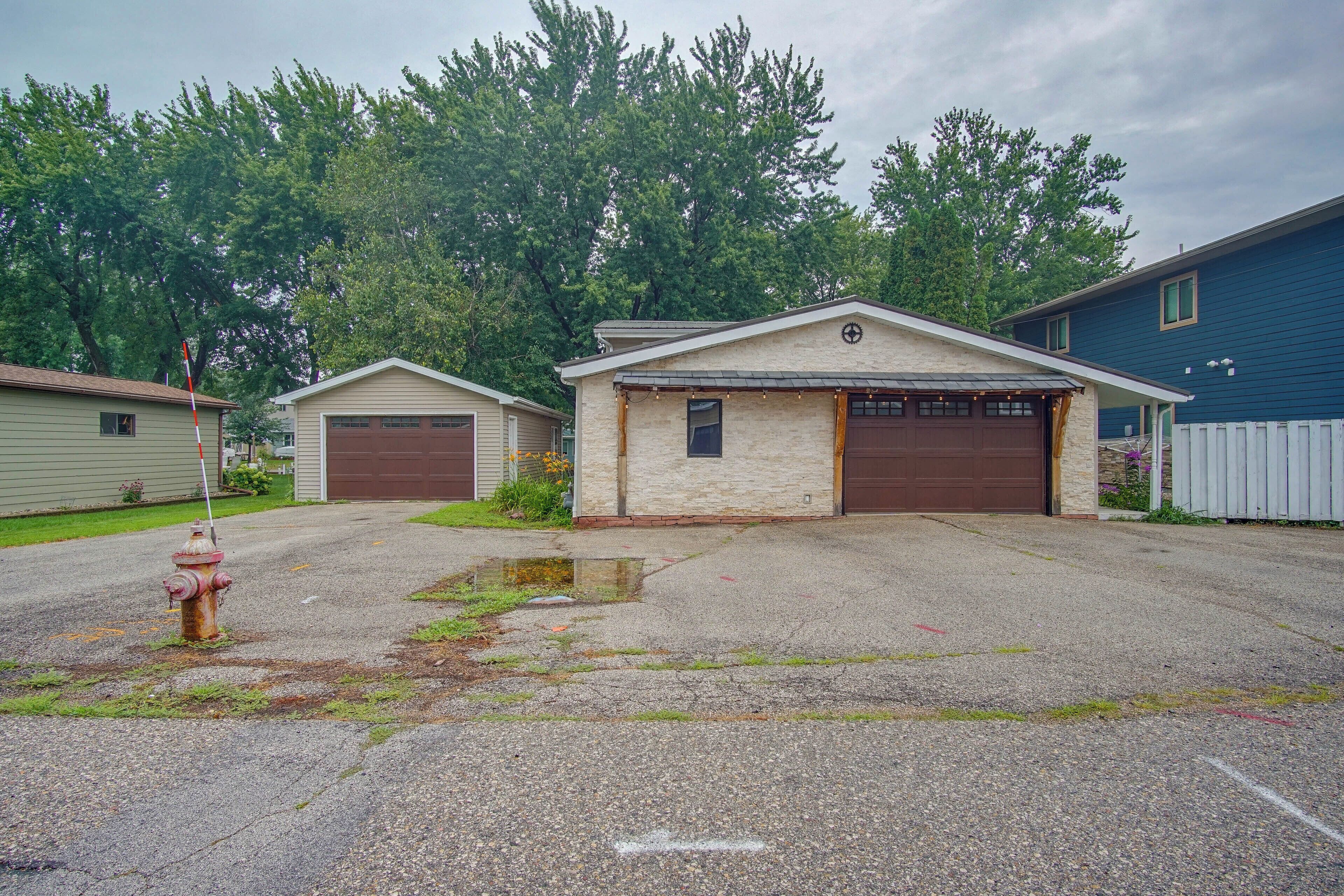 A residential property with a garage, a small attached building, and a fire hydrant.