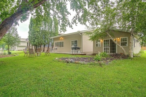 A single-story house with a covered porch, a lawn, and a tree providing shade.