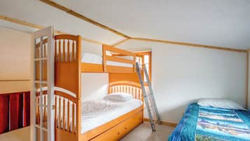A bunk bed with a ladder, a single bed with a quilt, and a wooden wardrobe.