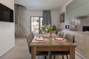 Ein moderner Essbereich mit einem Holztisch, gedeckt für vier Personen, einer Treppe und einer Küche mit einem großen Fenster.