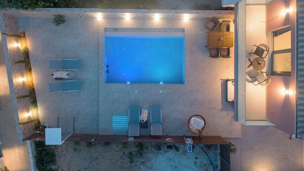Vista aerea di un giardino sul retro con piscina, mobili da esterno e zona patio.