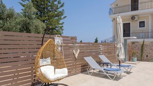 Un patio con un'amaca, poltrone relax e un recinto in legno.