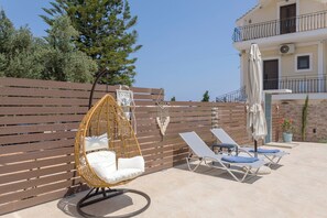Eine Terrasse mit Hängesessel, Liegestühlen und einem Holzzaun.