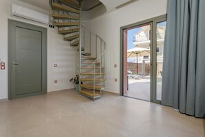 Eine Wendeltreppe mit Holzboden und Metallgeländern führt zu einem Balkon mit Blick auf Sitzgelegenheiten im Freien und ein Gebäude.