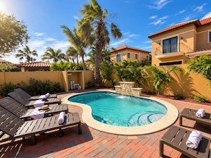 A swimming pool with lounge chairs and a stone wall. - Stylish 3BR villa in Gold Coast Aruba with private pool, gym, tennis courts and gated resort amenities. (Noord)