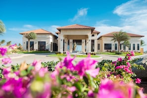 A hotel with a central courtyard, multiple buildings, and a statue. - Stylish 3BR villa in Gold Coast Aruba with private pool, gym, tennis courts and gated resort amenities. (Noord)