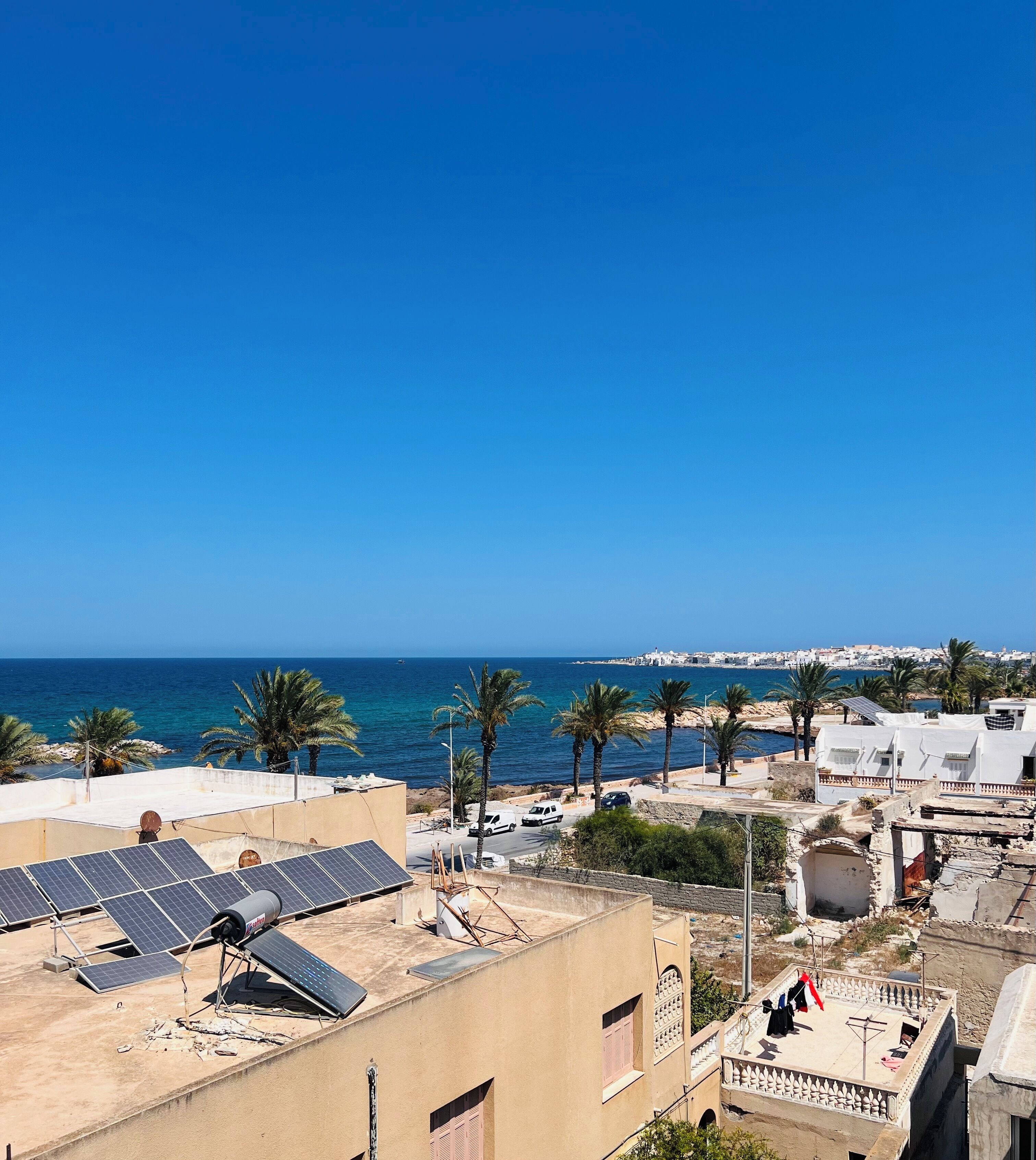 Une ville côtière avec des bâtiments, des panneaux solaires et un ciel bleu dégagé.