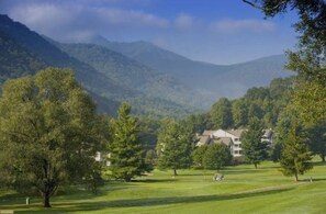 A golf course with a clubhouse and trees in the foreground, and mountains in the background. - Beautiful getaway at “Maggie Valley Resort” (Maggie Valley)