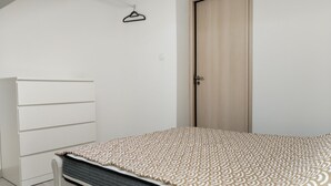 A bedroom with a bed, a wardrobe, and a door. - Comfortable and well-equipped accommodations (Ville-la-Grand)