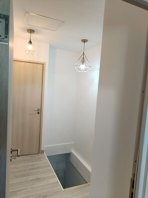 A hallway with a wooden door, a light fixture, and a small step leading to a lower level. - Comfortable and well-equipped accommodations (Ville-la-Grand)