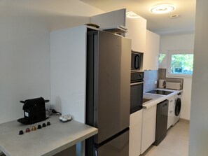 Eine kompakte Küche mit integriertem Kühlschrank, Mikrowelle und Geschirrspüler.