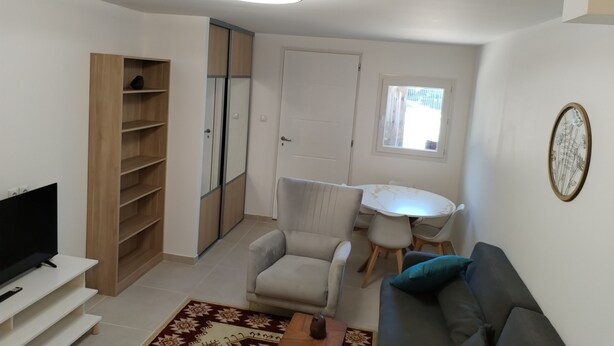 A modern living room with a flat-screen TV, a sofa, a coffee table, and a dining area with a table and chairs. - Comfortable and well-equipped accommodations (Ville-la-Grand)