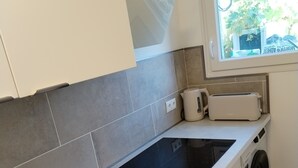 A modern kitchen with a built-in dishwasher, a toaster, and a window with a view of greenery outside. - Comfortable and well-equipped accommodations (Ville-la-Grand)