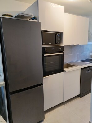 A modern kitchen with a stainless steel refrigerator, a microwave, and an oven. - Comfortable and well-equipped accommodations (Ville-la-Grand)