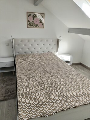 A bedroom with a tufted headboard, a patterned bedspread, a bedside table, and a nightstand. - Comfortable and well-equipped accommodations (Ville-la-Grand)