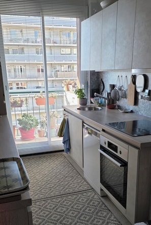 A modern kitchen with a large window, a sink, and a built-in oven. - Bed and Breakfast for Solo Female Travelers (Marseille)