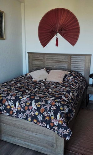 A bed with a floral bedspread, a wooden headboard, and a red fan hanging on the wall. - Bed and Breakfast for Solo Female Travelers (Marseille)