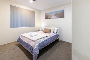 A bedroom with a bed, a window with blinds, a wall-mounted picture, and a carpeted floor. - Lovely Lake Treeby Home | 1 Min to Park & Playgrounds (Treeby)