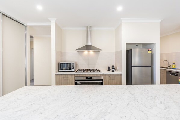 A modern kitchen with a marble countertop, stainless steel appliances, and wooden cabinets.