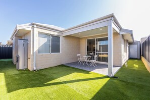 Ein modernes Haus mit Terrasse, Warmwasserbereiter und umzäuntem Garten.