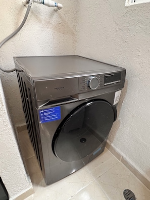 A compact, metallic washing machine with a digital display, a control knob, and a label indicating its capacity. - Beachfront apartment, colonial district (Santo Domingo Este)