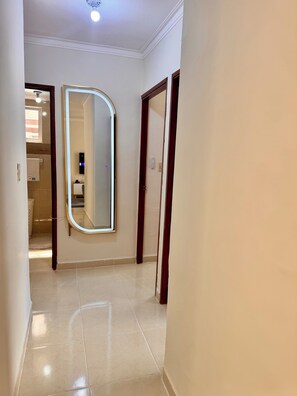 A hallway with a large mirror, a door, and a light fixture on the ceiling. - Beachfront apartment, colonial district (Santo Domingo Este)