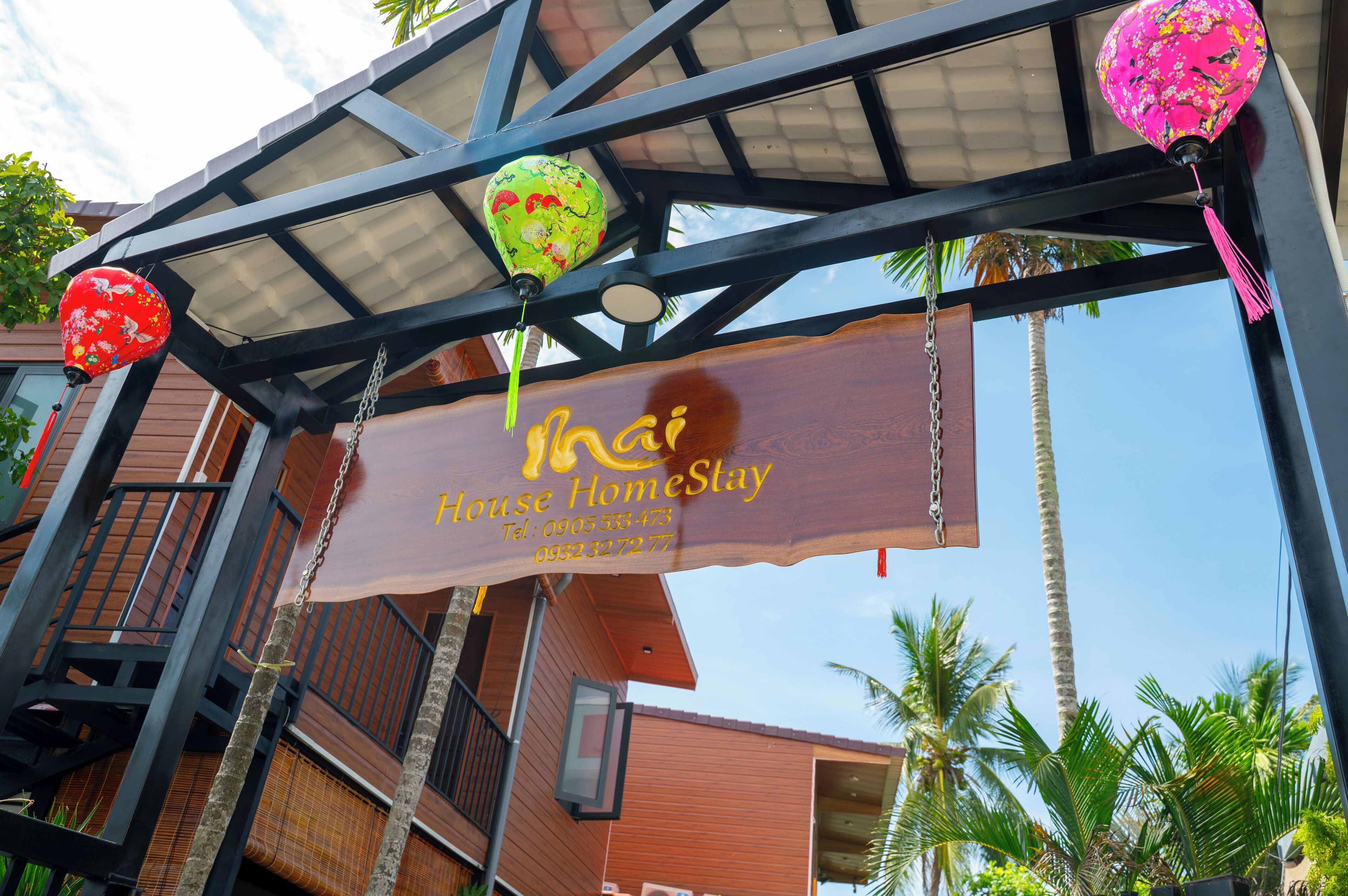 A hotel entrance with a sign reading 'House HomeStay' and contact information.
