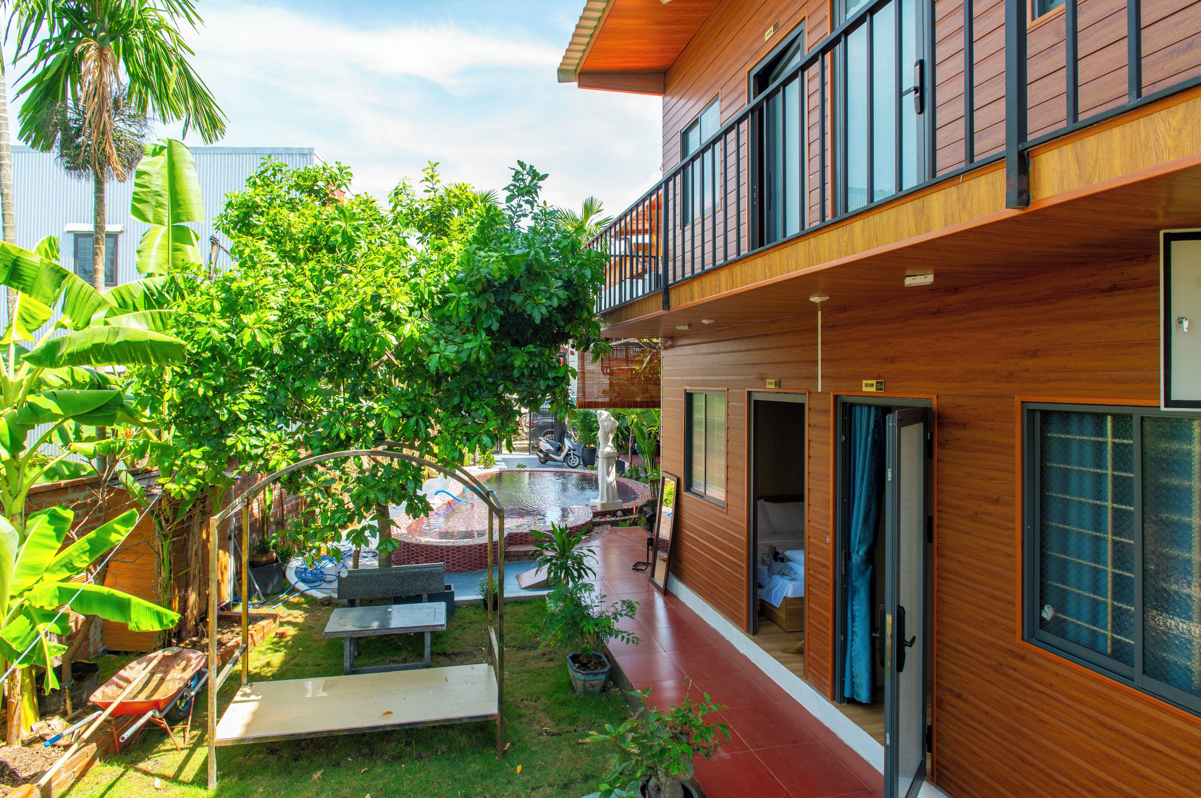 Un edificio moderno con fachada de madera, un balcón y un jardín con piscina.