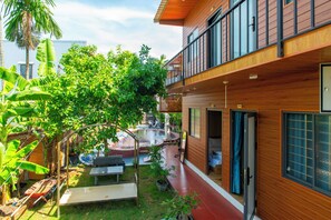 Un bâtiment moderne avec une façade en bois, un balcon et un espace jardin agrémenté d’une piscine.