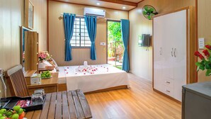 A hotel room with a bed, a desk with a chair, a wardrobe, and a TV. - Mai House Homestay (Da Nang)