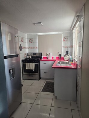 A kitchen with a stainless steel refrigerator, a microwave, a stove, and a sink. - Green haven studio (Oranjestad)