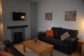 A living room with a fireplace, a sofa, a coffee table, and two paintings on the wall.
