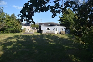 A residential property with a detached house, a garage, and a fenced yard. - Snowdonia Riverside Cabin With Private River (Caernarfon)