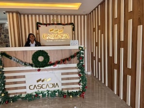 Ein Empfangsschalter mit weihnachtlichem Kranz und Girlande, auf dem der Name 'CASCADIA' gut sichtbar angebracht ist.