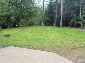 A grassy area with a concrete path leading into a wooded area. - 7 Pines Cabin Hunt, Fish & Ride (Mountain)