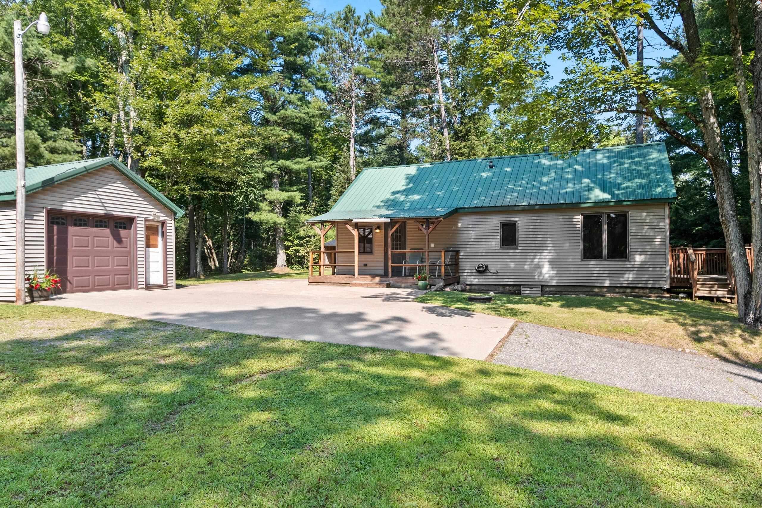 A two-story cabin with a green roof, a garage, and a covered porch.