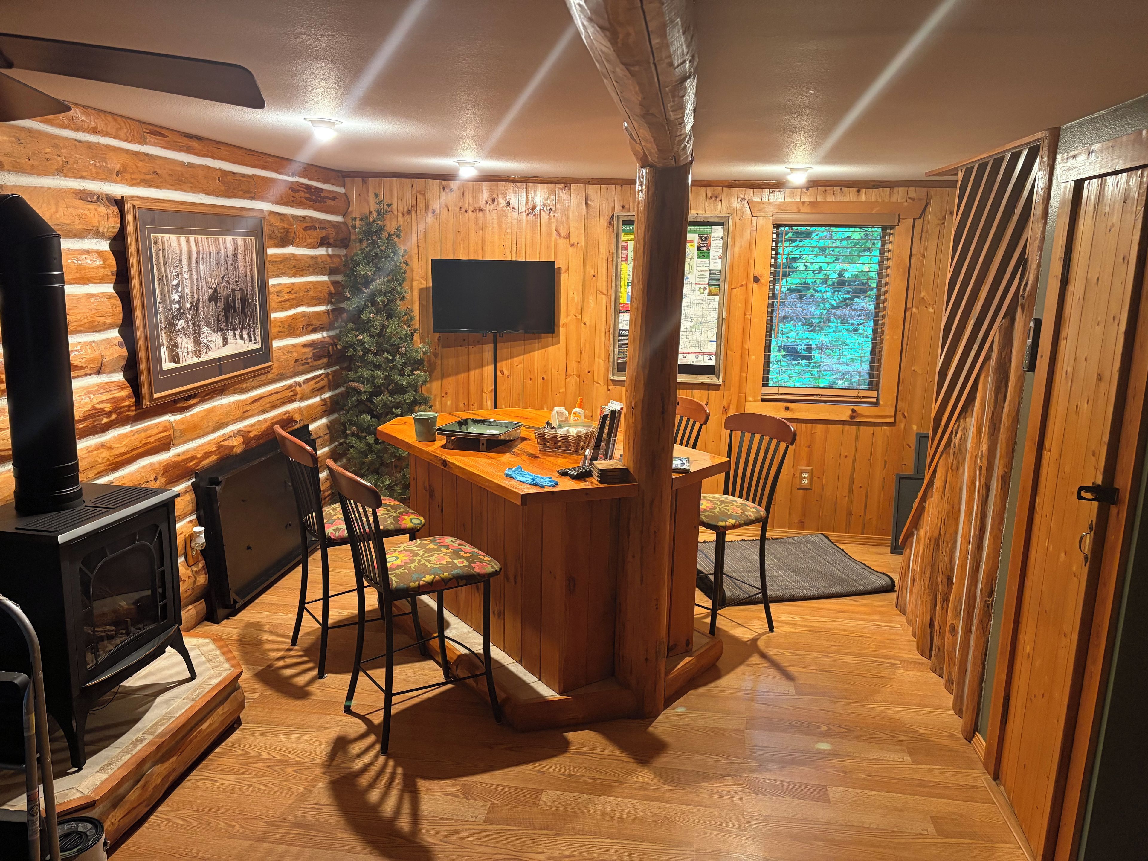 L’intérieur d’une cabane en rondins comprend une cheminée, un coin repas et un téléviseur.