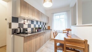 Een moderne keuken met houten kastjes, een zwart-wit betegelde achterwand en een eethoek met een tafel en stoelen.