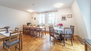 Een eetruimte met houten tafels en stoelen, een raam met gordijnen en een radiator.