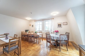 A dining area with wooden tables and chairs, a window with curtains, and a radiator. - Wonderful 9-bedroom villa in Karlovy Vary for your getaway (Karlovarský kraj)