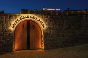 A stone wall with a wooden double door labeled 'GAPPA HISAR CAVE HOUSE' and a sign above it. - Cappa Hisar Cave House (Ortahisar)