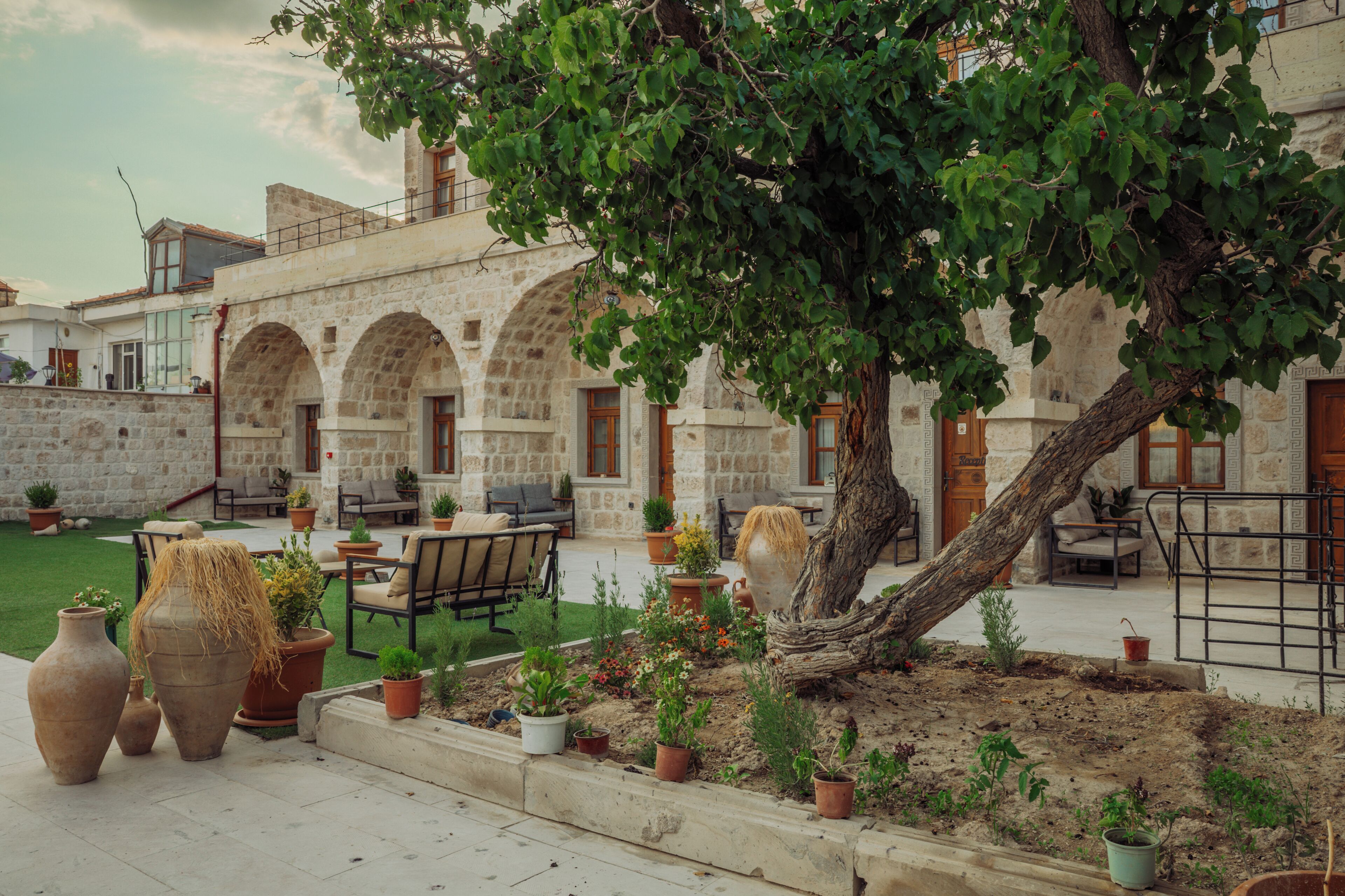 A courtyard with stone arches, outdoor seating, and potted plants.